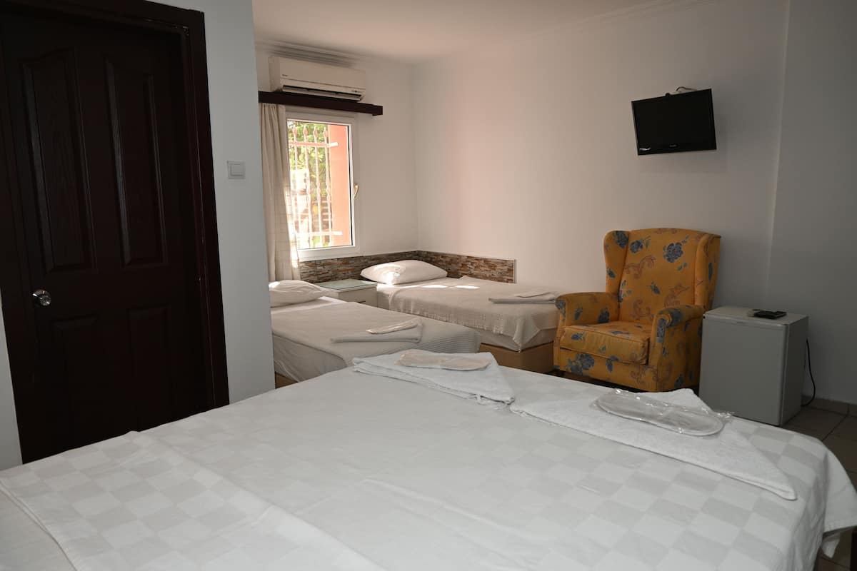 A hotel room with a bed, two bedside tables, a chair, a TV, and a window.