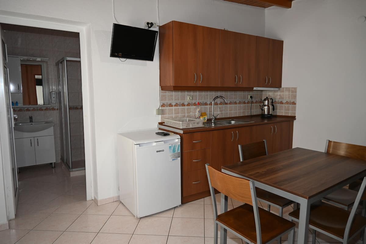 A compact kitchen with wooden cabinets, a refrigerator, a sink, and a dining table with chairs.