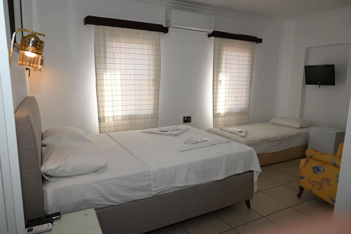 A room with two beds, a TV, and an air conditioning unit.