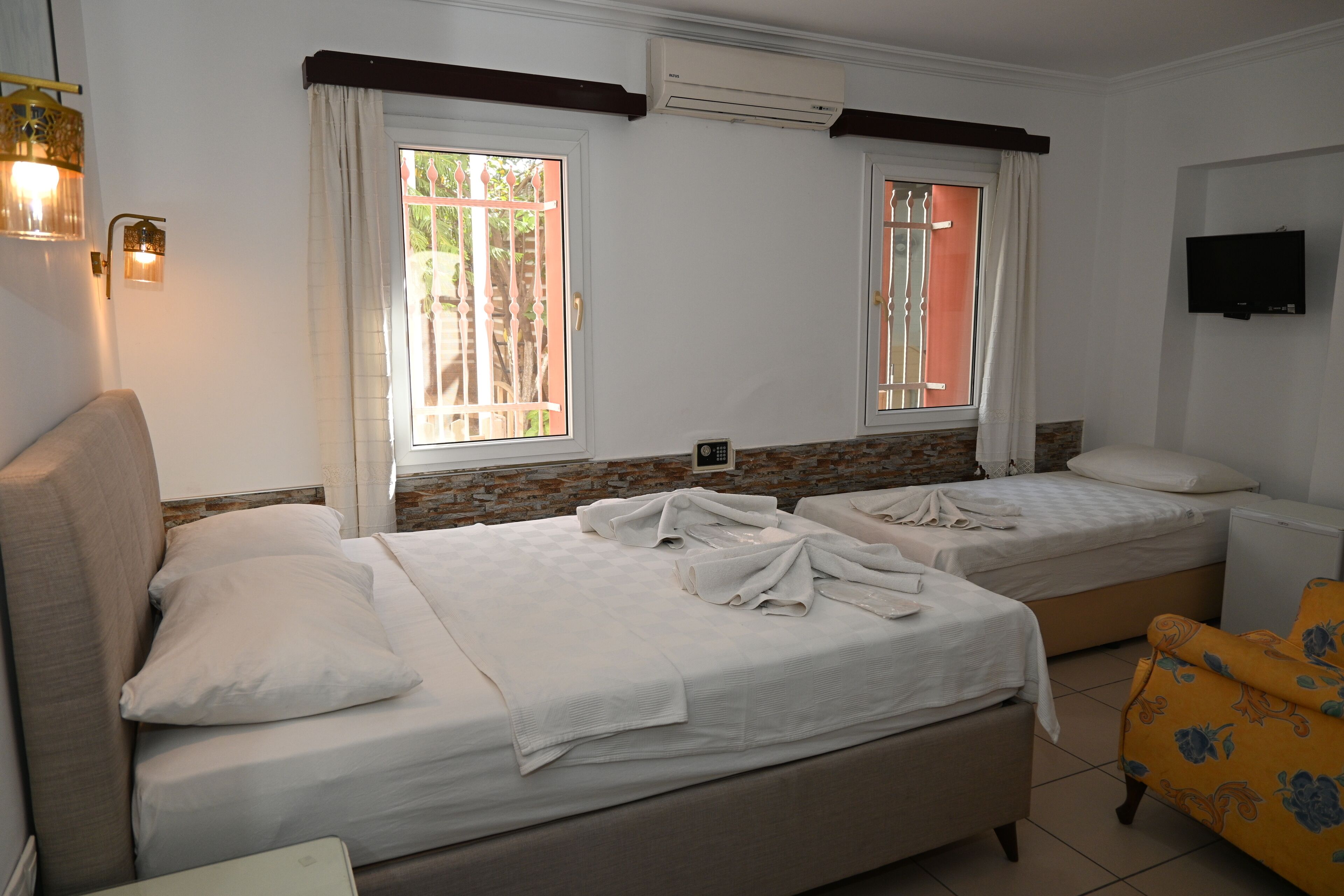 Una habitación de hotel con dos camas, un sofá, un televisor y una ventana con cortinas.