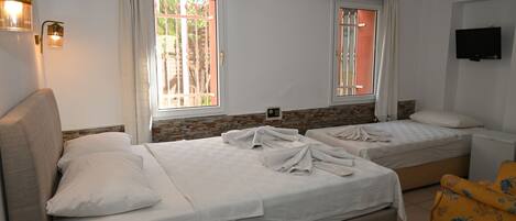 Una habitación de hotel con dos camas, un sofá, un televisor y una ventana con cortinas.