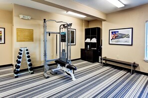 A gym with a weight bench, a squat rack, and a wall-mounted sign. - Candlewood Suites Manhattan by IHG (Manhattan)