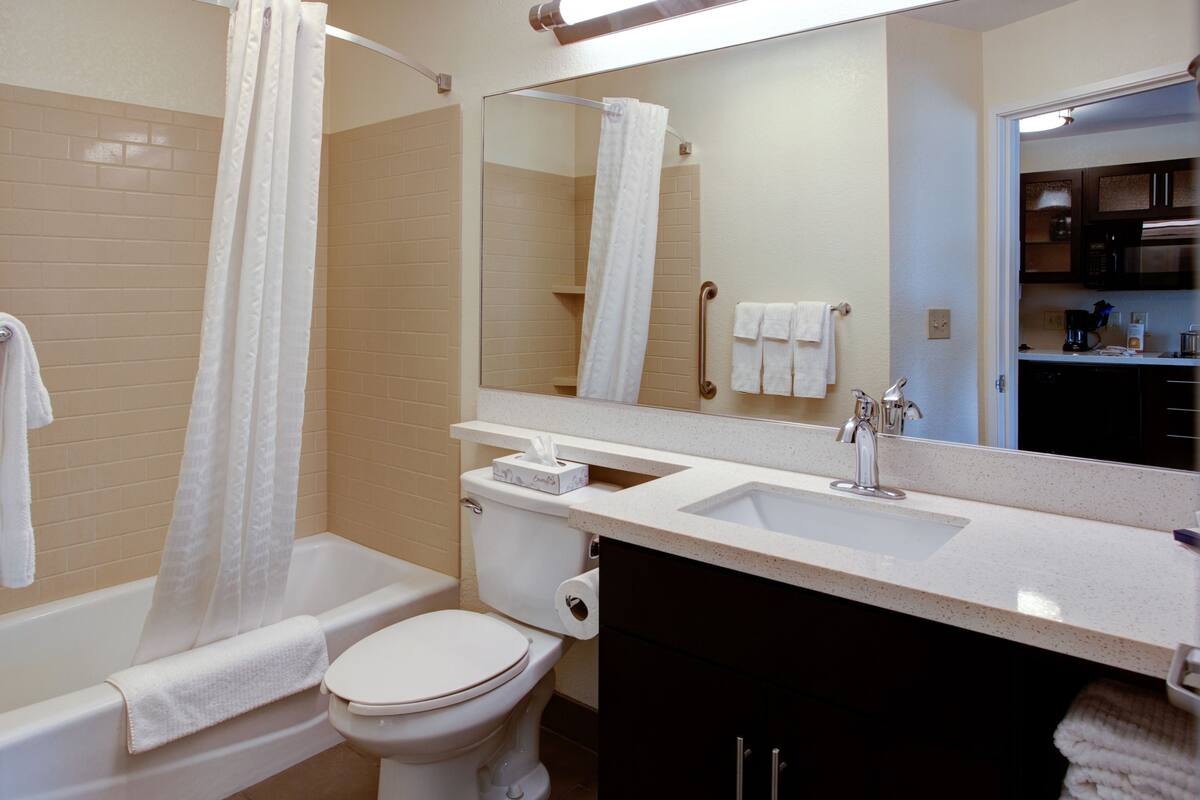 A bathroom with a bathtub, toilet, sink, and a mirror.