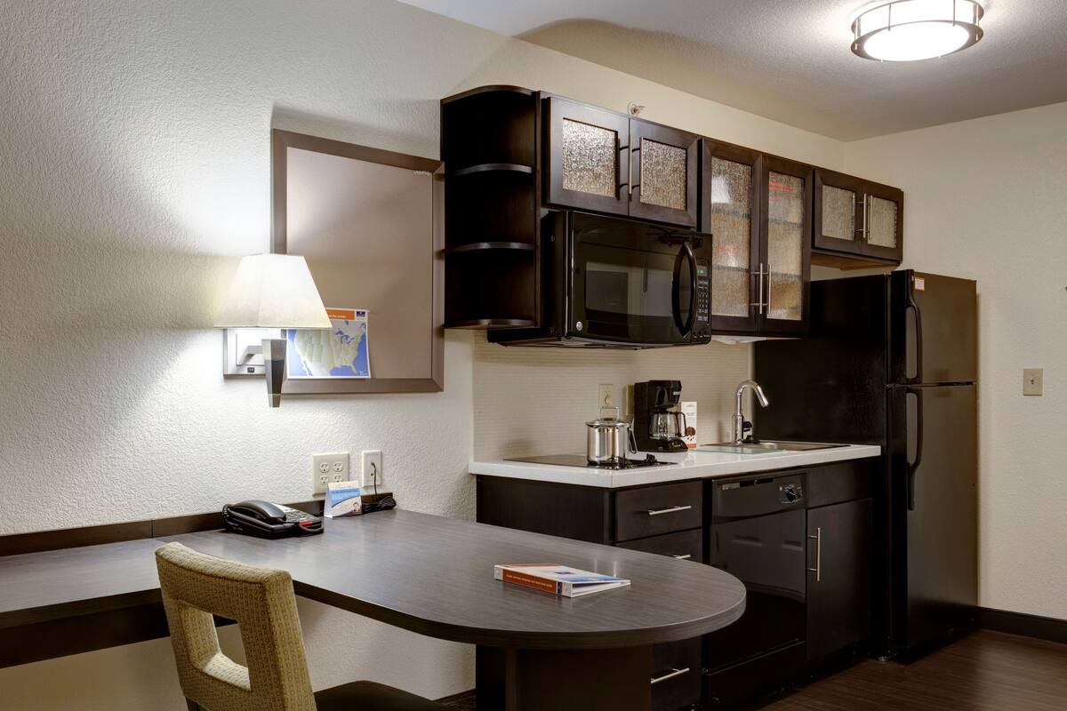A compact kitchen with dark cabinetry, a microwave, a refrigerator, and a coffee maker.