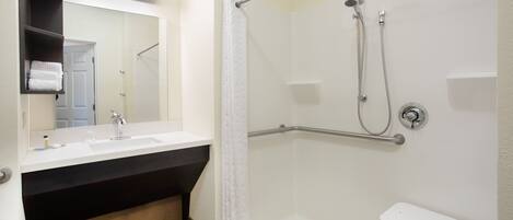 A bathroom with a shower, a sink, and a mirror.