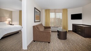 Ein Hotelzimmer mit Bett, Sofa, Fernseher und Schreibtisch.