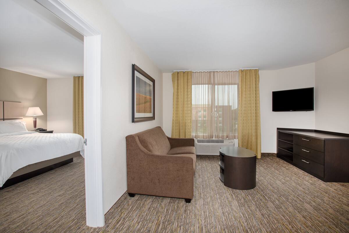 A hotel room with a bed, a sofa, a TV, and a desk.