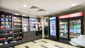 A snack and beverage kiosk with a variety of snacks, a microwave, and a refrigerator stocked with drinks. - Candlewood Suites Manhattan by IHG (Manhattan)