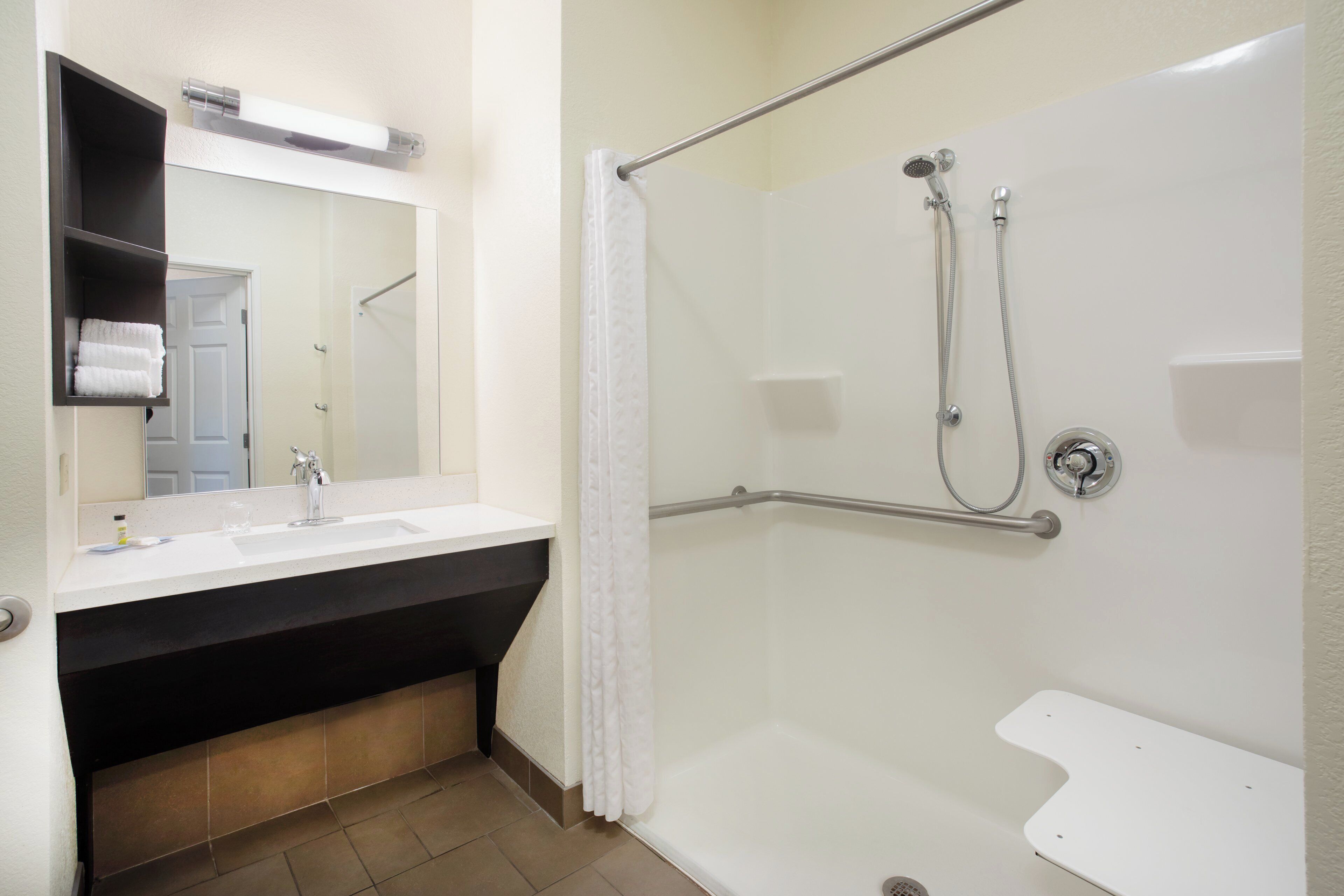 Un baño con ducha, lavamanos y espejo.