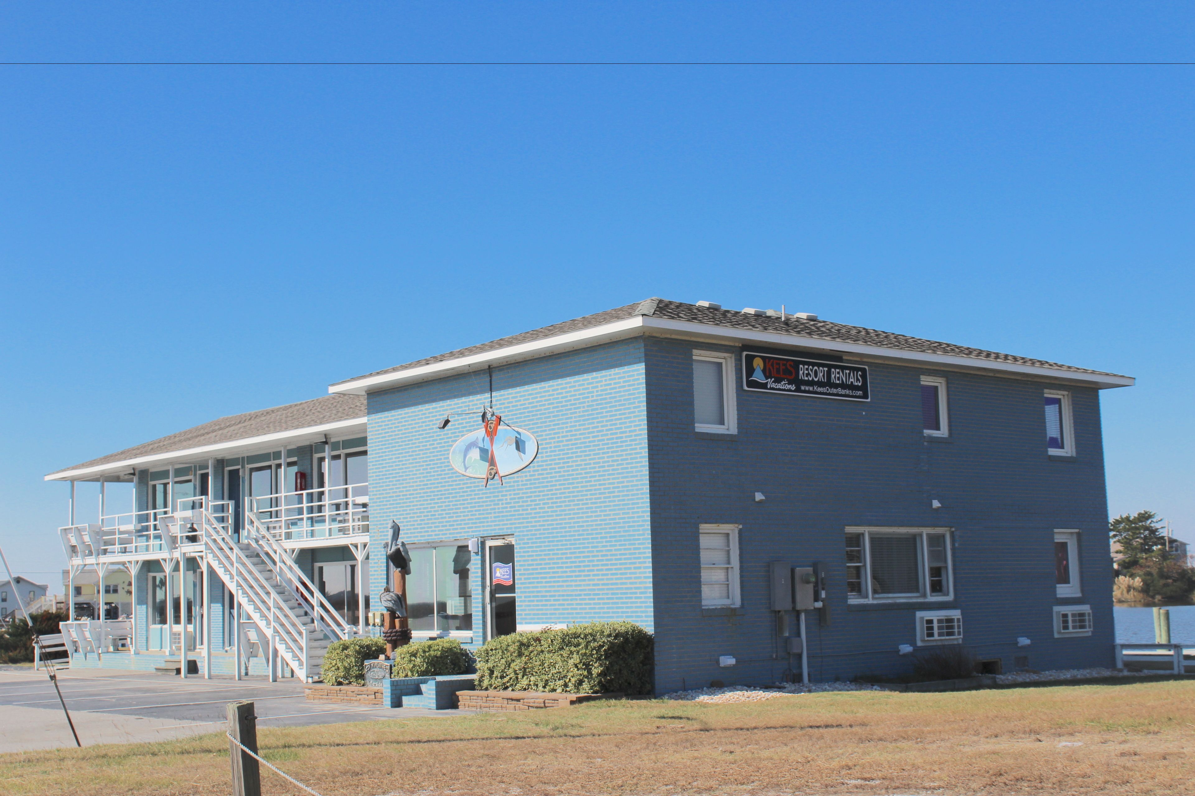 A two-story building with a blue exterior, a sign for 'Resort Rentals', and a staircase leading to the upper floor.