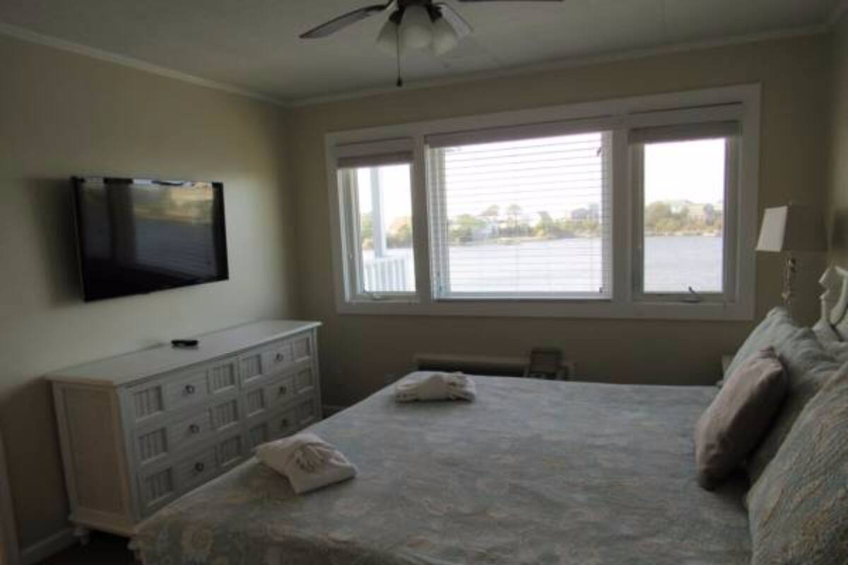 A bedroom with a bed, a dresser, a television, and a window with blinds.
