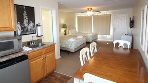 A compact living space with a kitchenette, a dining area, and a bedroom with a bed and curtains. - Fin 'n Feather Waterside Inn By Kees Vacations (Nags Head)