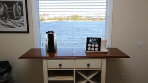 A kitchen counter with a coffee maker, Kees Vacation sign, and a framed photo. - Fin 'n Feather Waterside Inn By Kees Vacations (Nags Head)