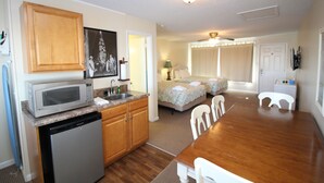 A compact hotel room with a kitchenette, a bed, a bathroom, and a dining area. - Fin 'n Feather Waterside Inn By Kees Vacations (Nags Head)