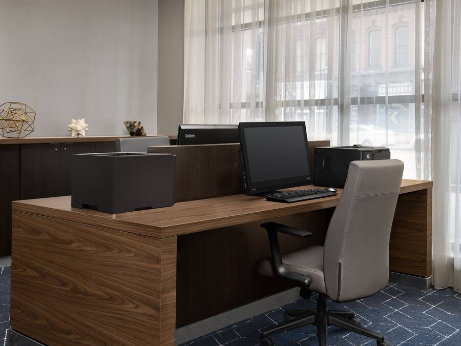 A modern office desk with a laptop, a desktop computer, and a printer.