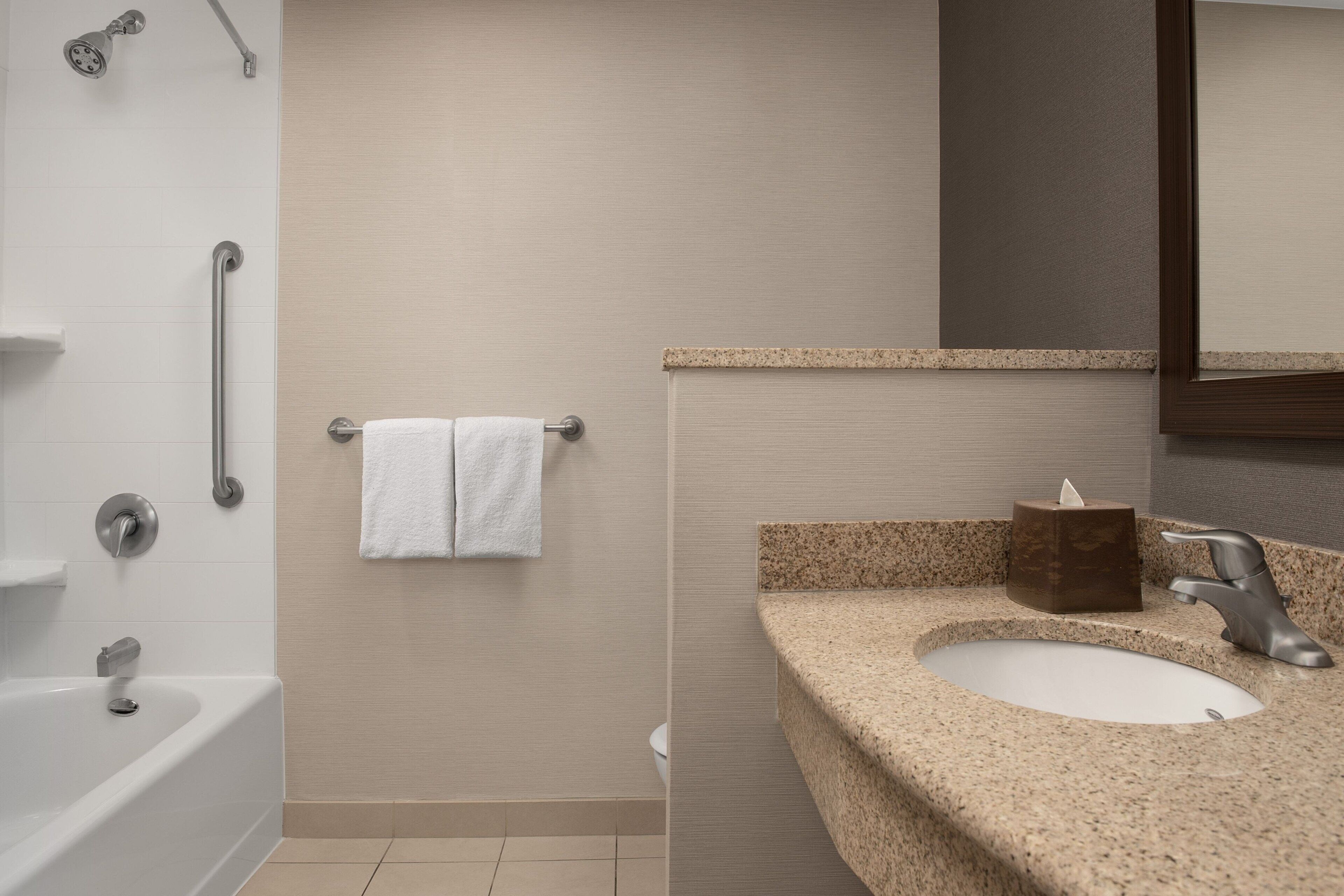 A bathroom with a bathtub, a sink, a towel rack, and a mirror.