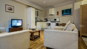 A modern living room with a television, a wooden coffee table, and a sofa. - The Gables Guest House (Lincoln)