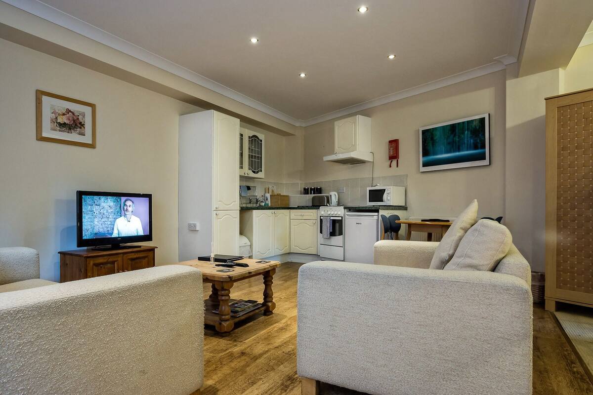 Una sala de estar moderna con televisor, una mesa de centro de madera y un sofá.