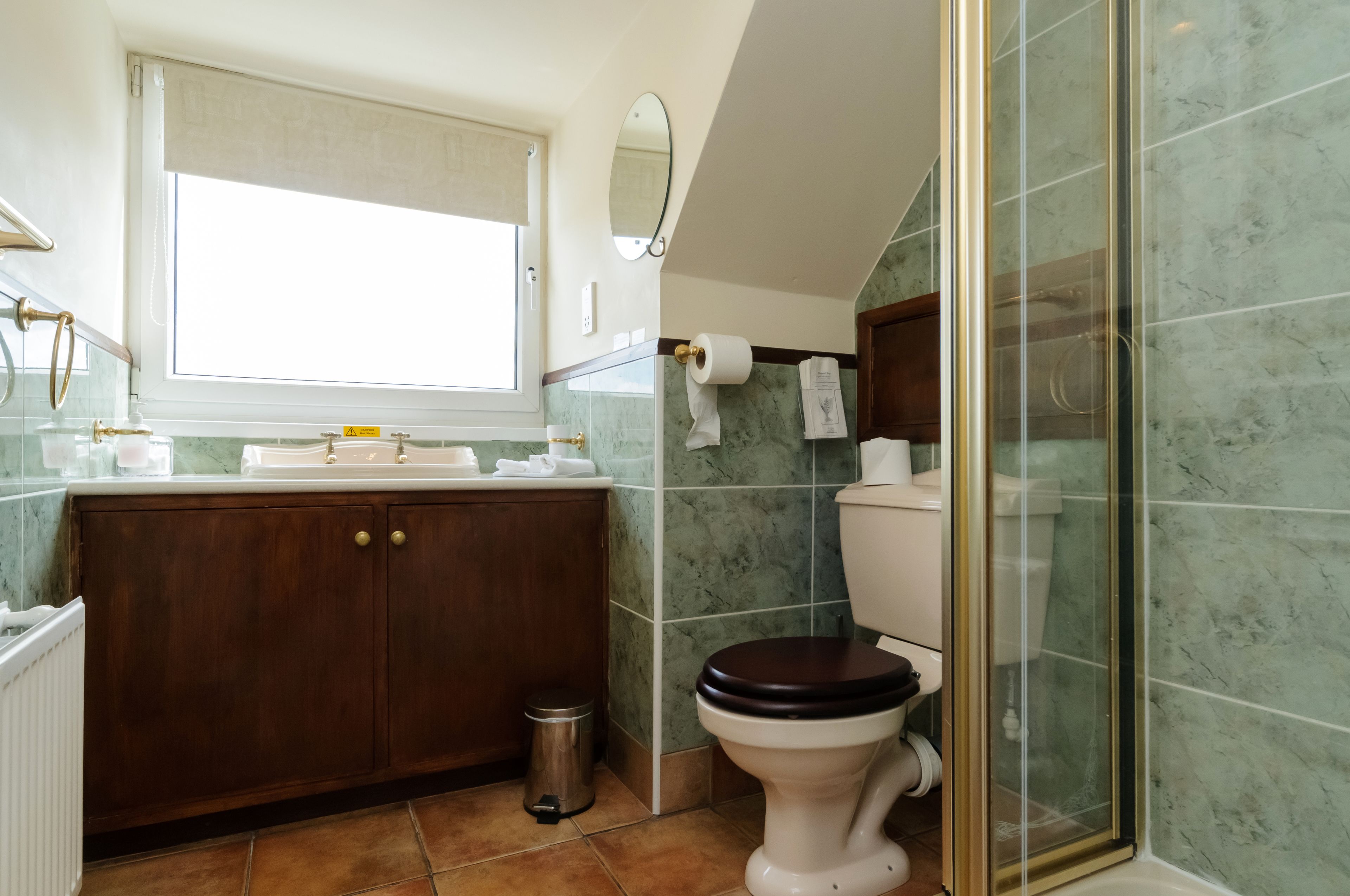 A bathroom with a wooden vanity, a toilet, and a glass shower enclosure.
