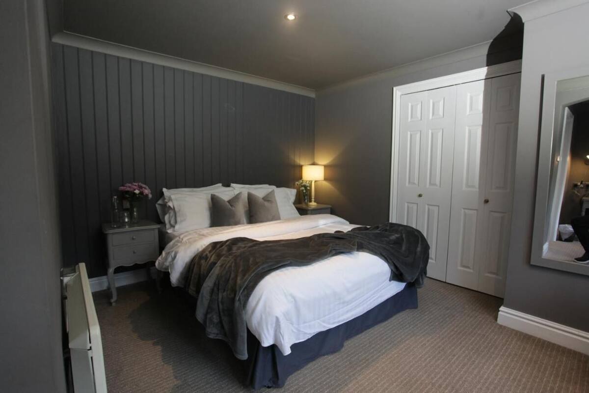 A bedroom with a bed, bedside table, lamp, and a wardrobe.