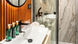 Une salle de bain moderne avec un lavabo en marbre, un lambris en bois, une douche en verre et un grand miroir.