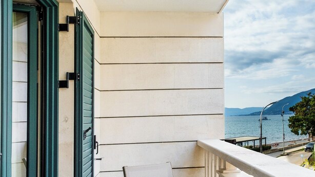Un balcon avec une table et des chaises, donnant sur une étendue d’eau et sur une montagne lointaine.