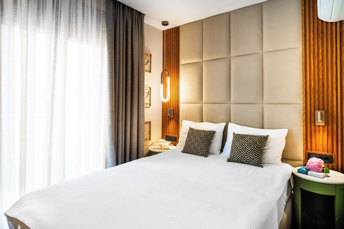 Habitación de hotel con una cama grande, una mesita de noche y una lámpara de pared.