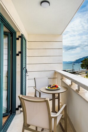 Un balcón con mesa y sillas, un plato de fruta y vistas al mar.