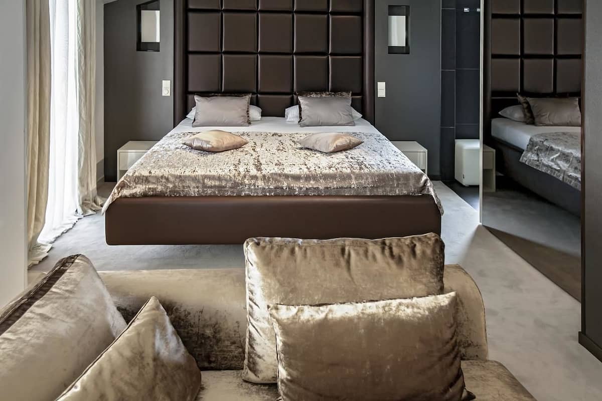 Een moderne slaapkamer met een groot bed, een bank en een klein tafeltje.