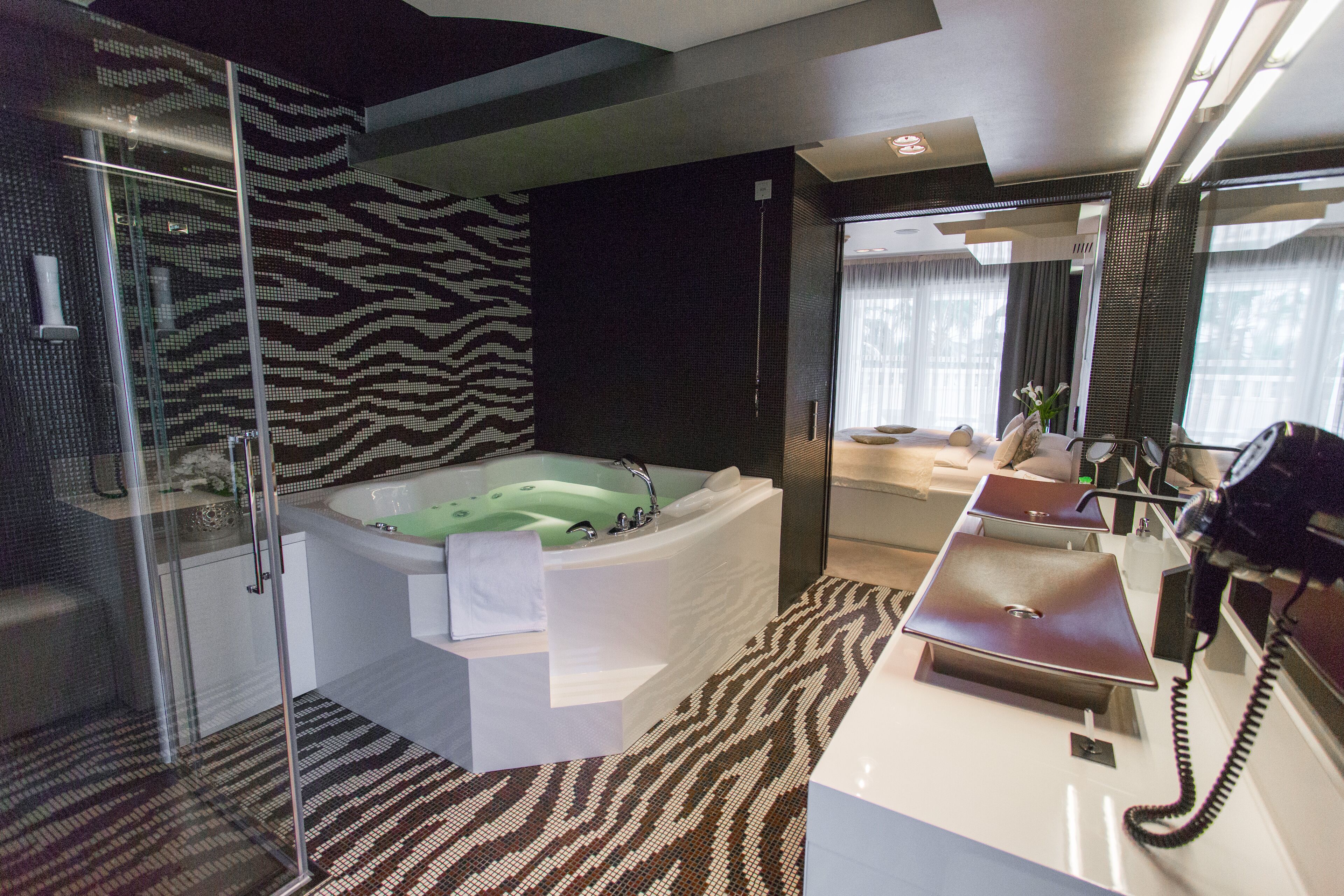 Un baño moderno con una bañera grande, una ducha con mampara de vidrio y un tocador con espejo.