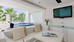 Een moderne woonkamer met een witte bank, een glazen salontafel en een flatscreen televisie aan de wand.
