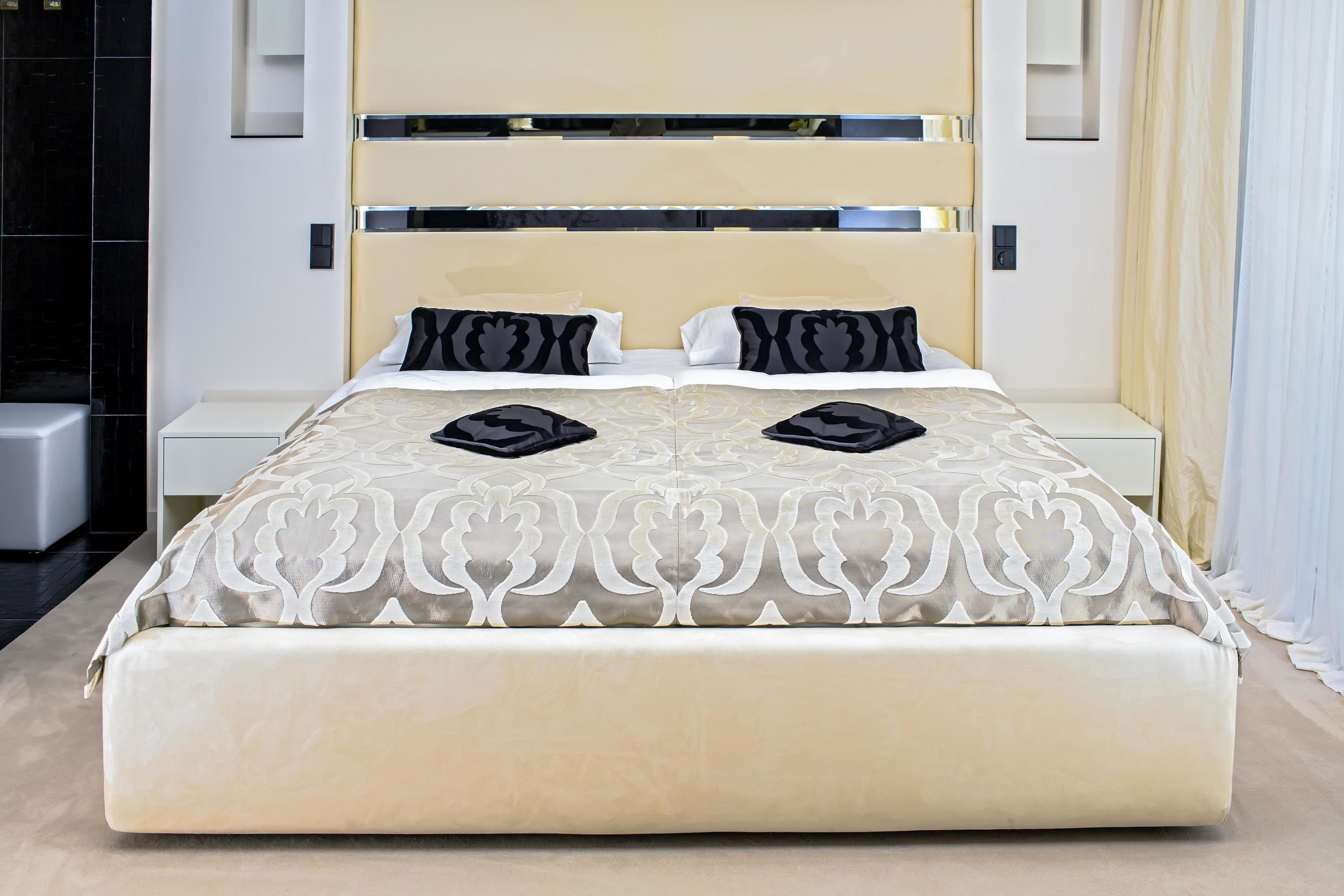 A modern hotel room with a large bed, a bedside table, and a nightstand.