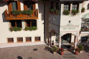 Een klassiek Europees hotel met balkon, bloembakken en een kinderaardse binnenplaats.