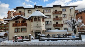 A hotel with a traditional architectural style, featuring balconies and a snow-covered entrance. - Hotel Majorka (Andalo)