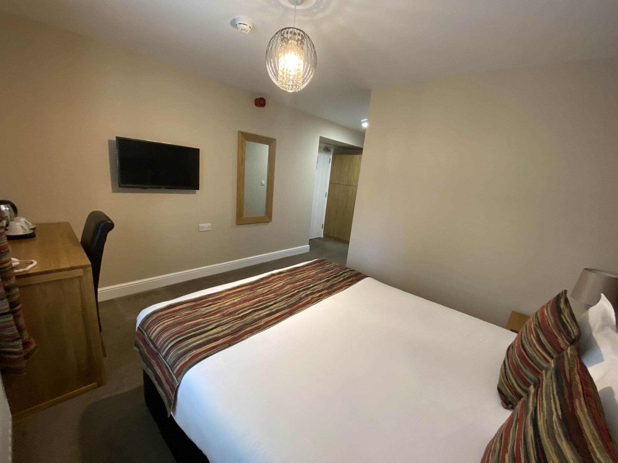 Une chambre d’hôtel équipée d’un lit, d’un bureau, d’une chaise, d’une télévision et d’un miroir.