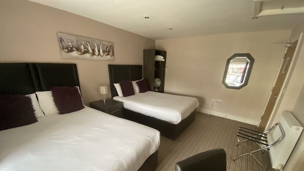 A hotel room with two beds, a desk, a chair, a small table, a mirror, and a picture on the wall.