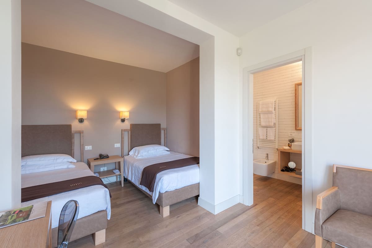 Una habitación de hotel con dos camas, mesitas de noche, un escritorio y una silla.