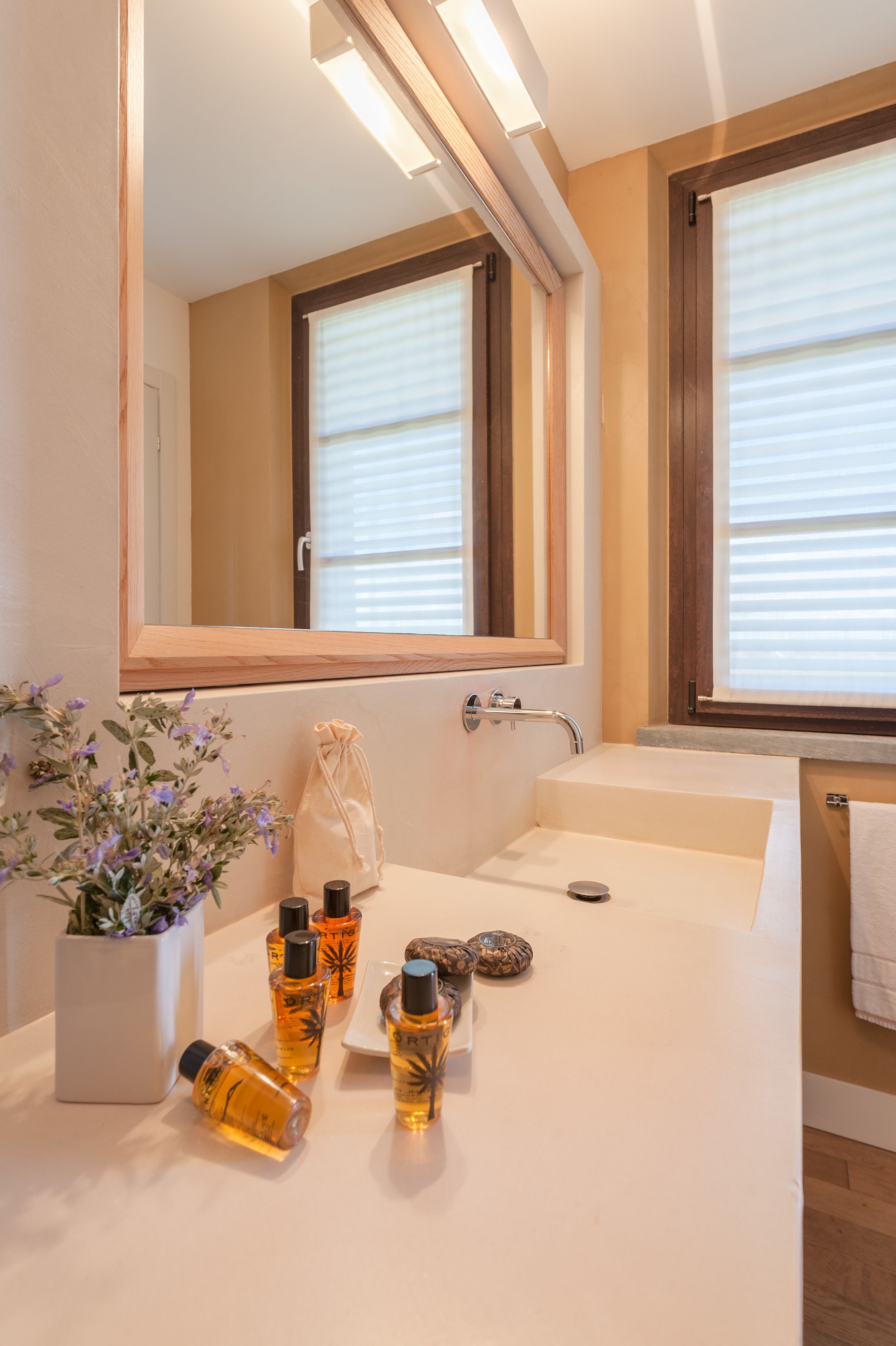 A bathroom with a large mirror, a sink, and a potted plant.
