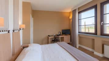 Habitación de hotel con cama, escritorio y vista al campo.