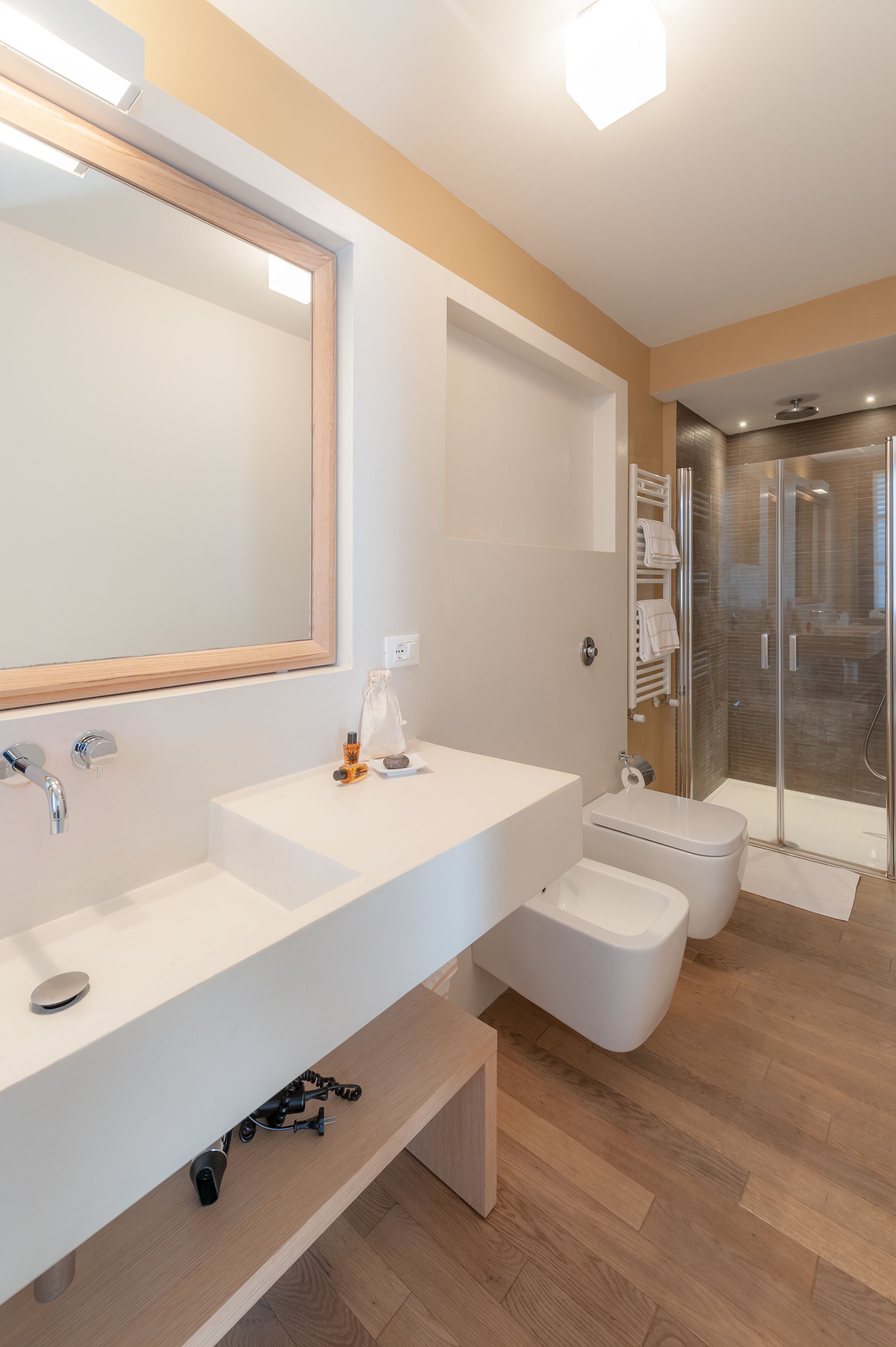 A modern bathroom with two sinks, a toilet, a shower, and a large mirror.
