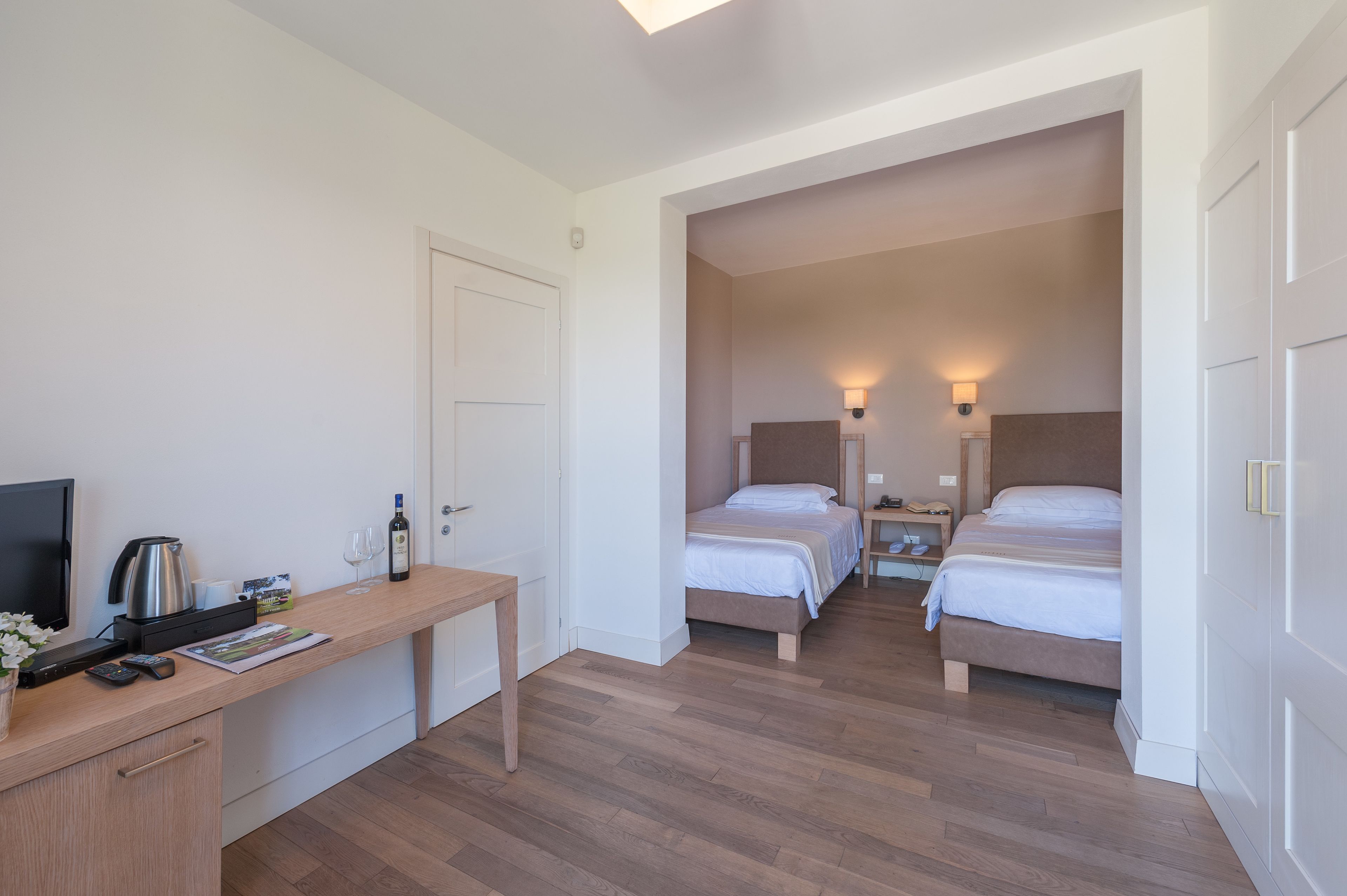 Une chambre d’hôtel avec un bureau en bois, une télévision, un lit et une table de chevet avec une lampe.