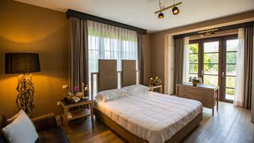 A spacious bedroom with a large bed, a bedside table with a lamp, a dresser, and a window with curtains.