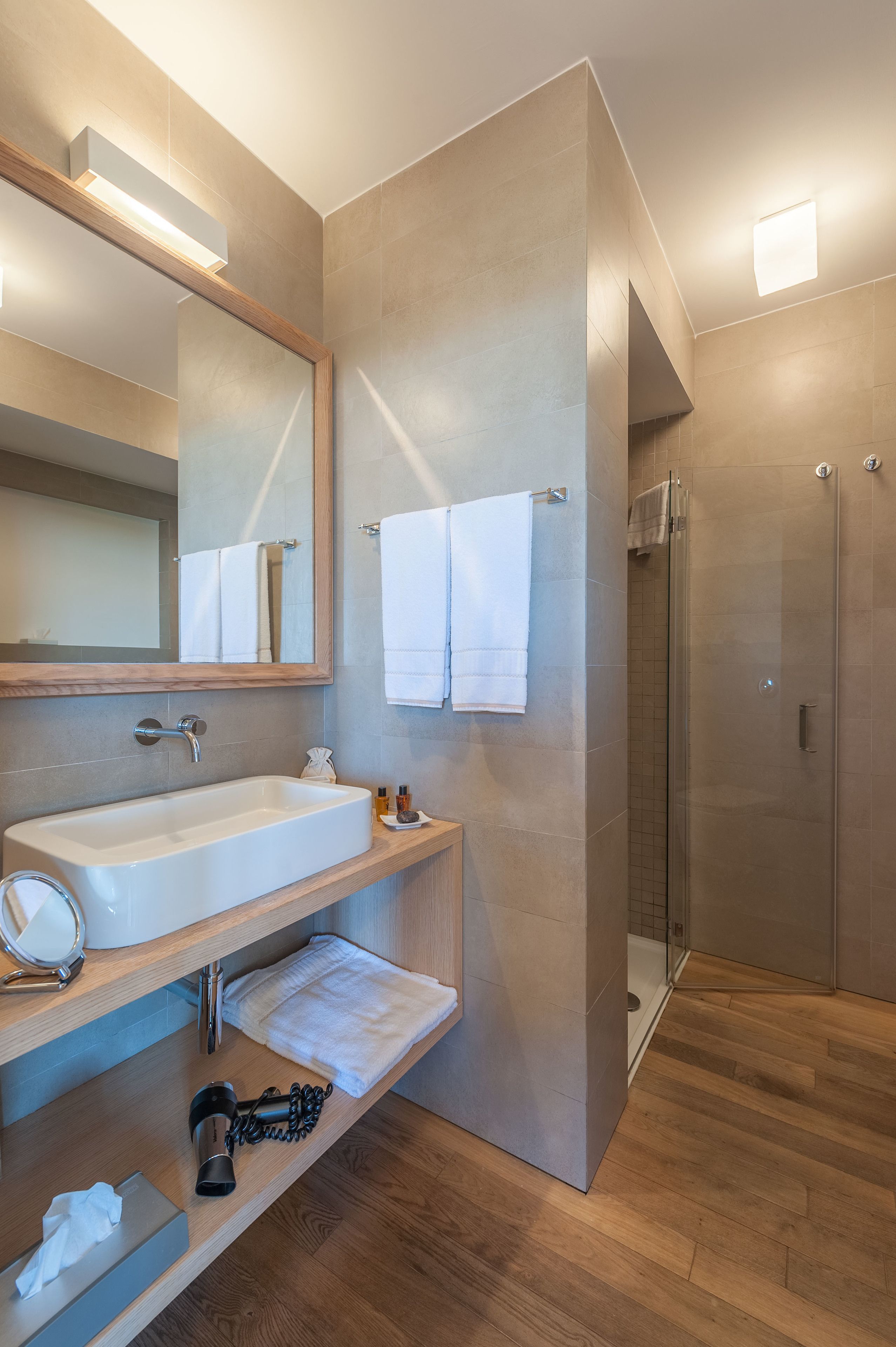A modern bathroom with a large mirror, a sink, a towel rack, and a glass shower enclosure.