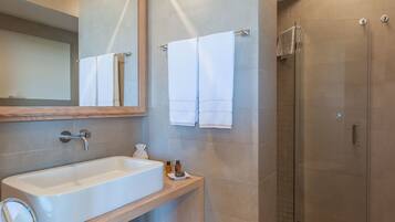 A modern bathroom with a large mirror, a sink, a towel rack, and a glass shower enclosure.