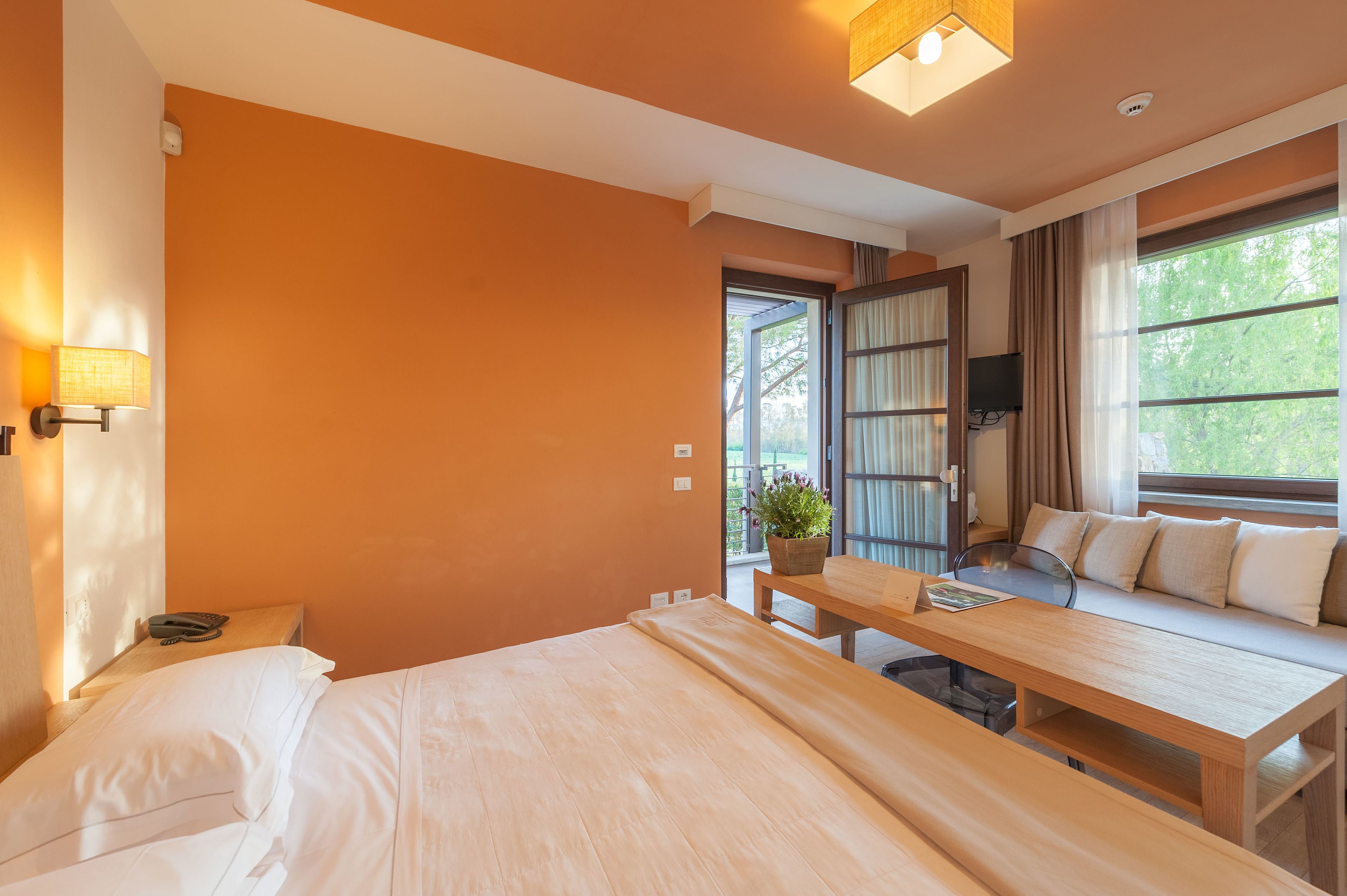 Habitación de hotel con cama, escritorio, sofá y ventana con cortinas.