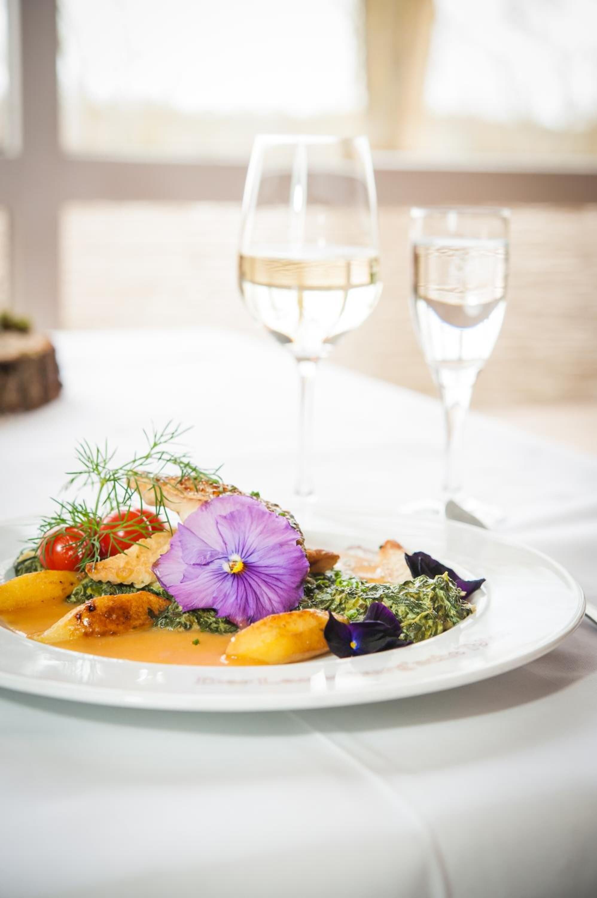 Une assiette de nourriture et un verre de vin blanc sur une table.
