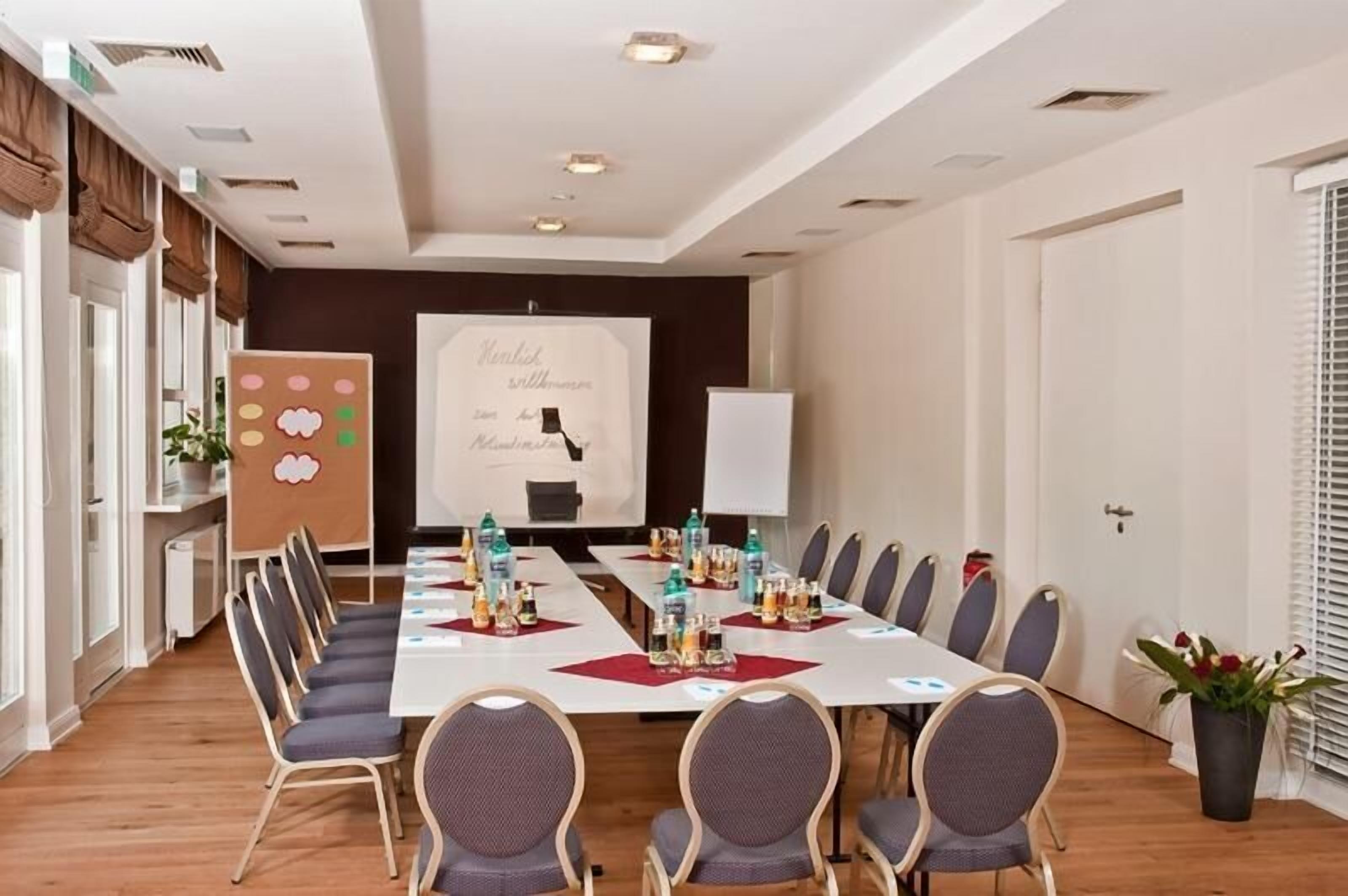 A conference room with a long table, chairs, and a presentation screen.