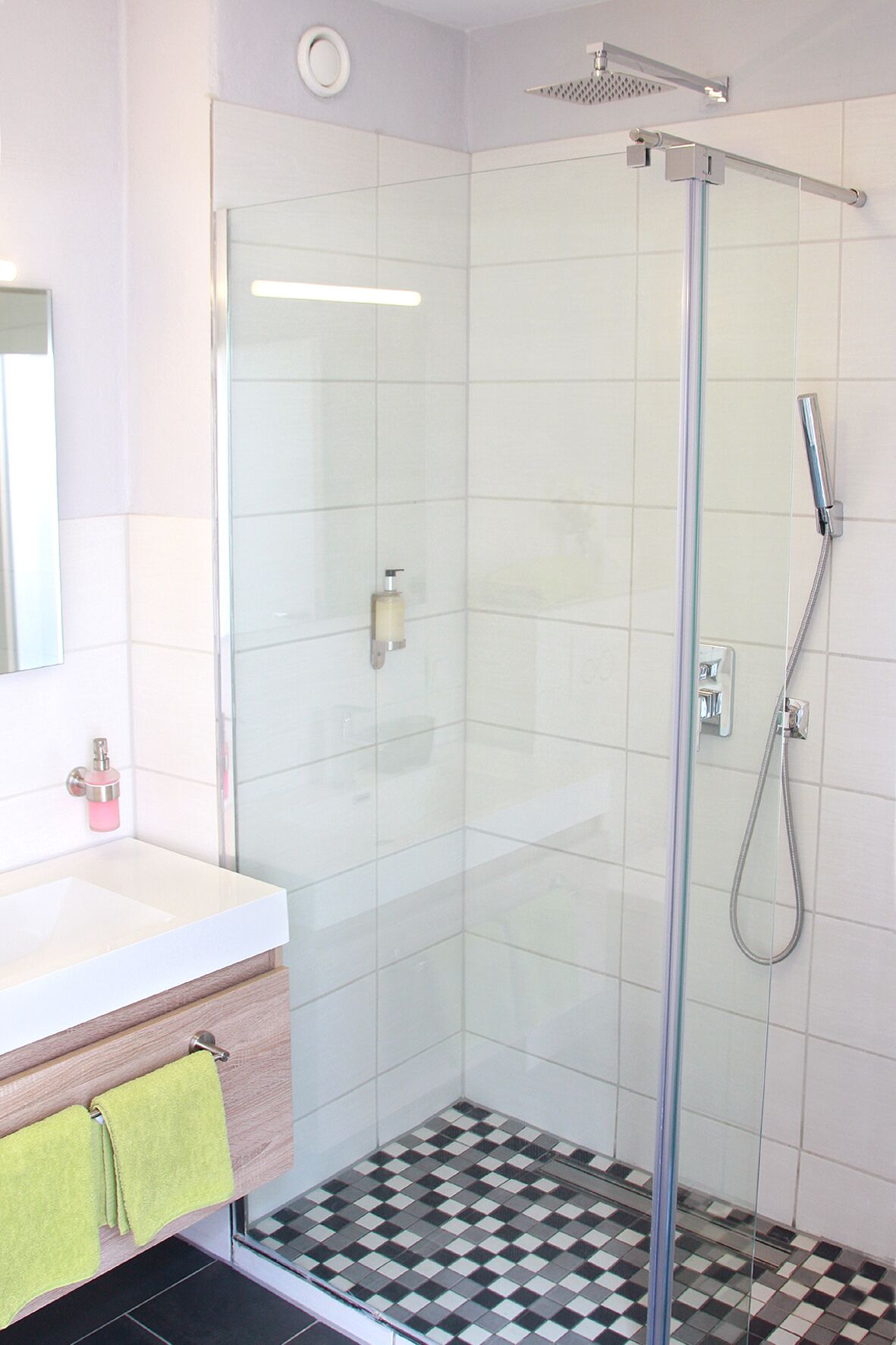 A modern bathroom with a glass-enclosed shower, a white sink, and a checkered floor.