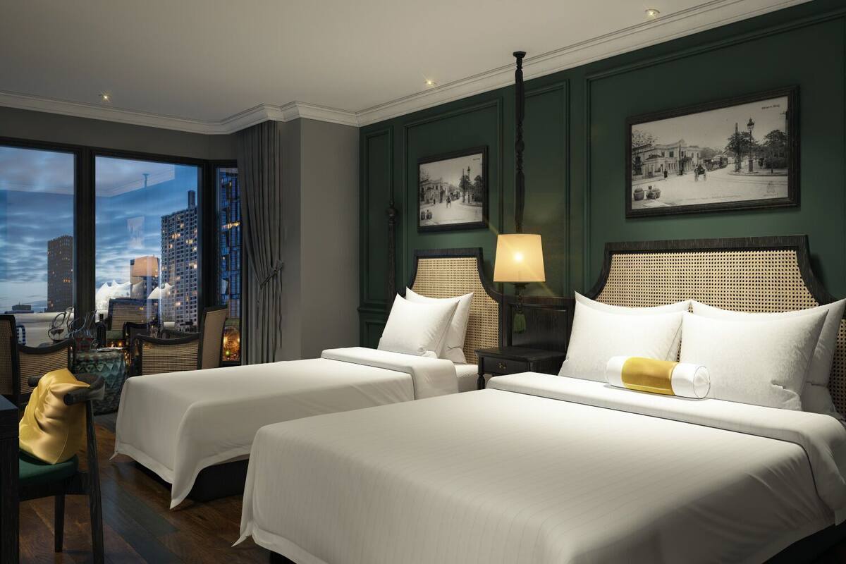 Habitación de hotel con dos camas, vistas a la ciudad y un área de comedor con vistas.