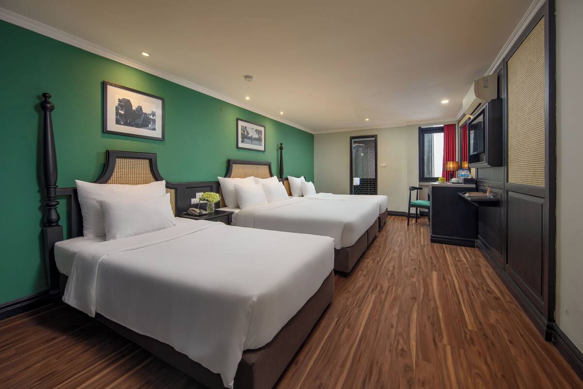 Una habitación de hotel con dos camas, un escritorio y una televisión.